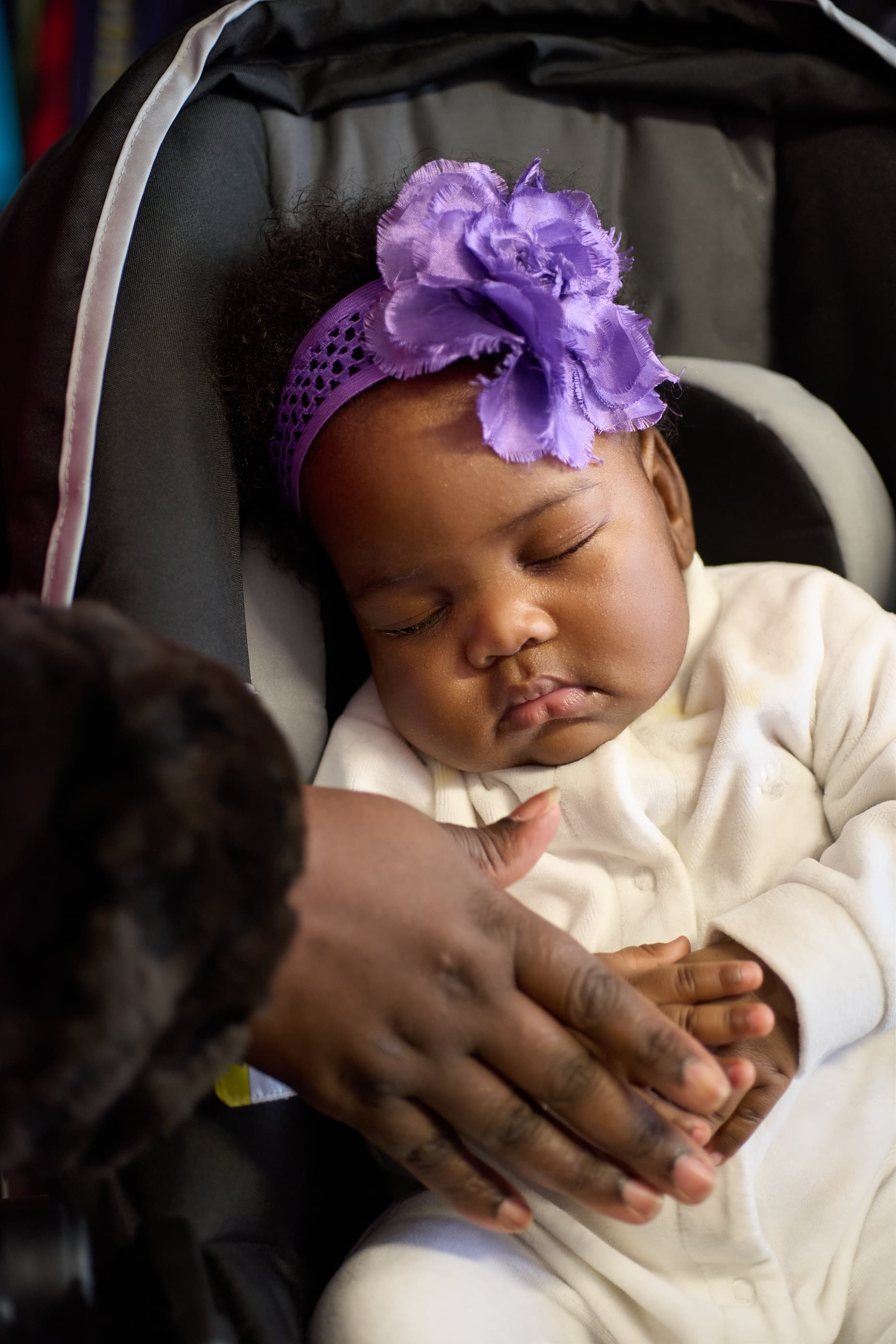 A baby held close in a car seat at Cradle & Kind Baby Boutique